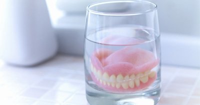 Dentures soaking in a glass