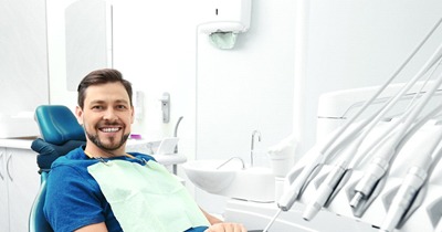 Man in blue shirt smiling in dental chair