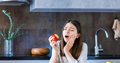 person holding their mouth after biting into an apple