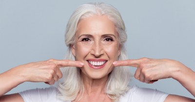 Older woman pointing to flawless smile