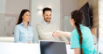 Couple shaking hands with a dental employee