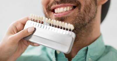 a cosmetic dentist holding up a tooth color-shade chart