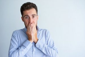 Concerned man covers his mouth after his dental crown breaks