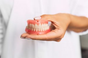 dentist holding a set of full dentures 