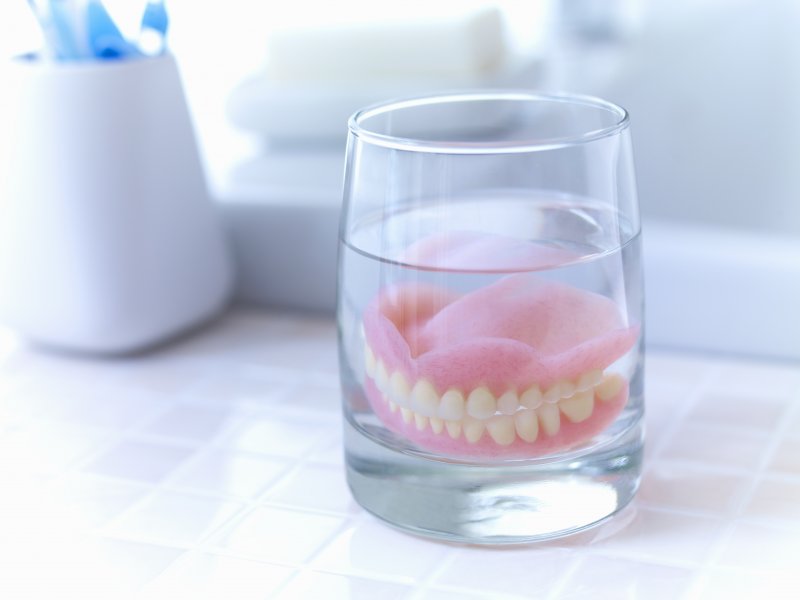 A soaking denture next to a sink