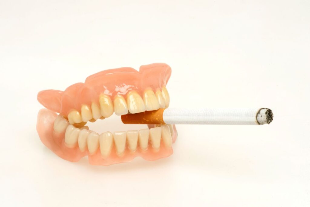 A pair of dirty dentures biting a cigarette